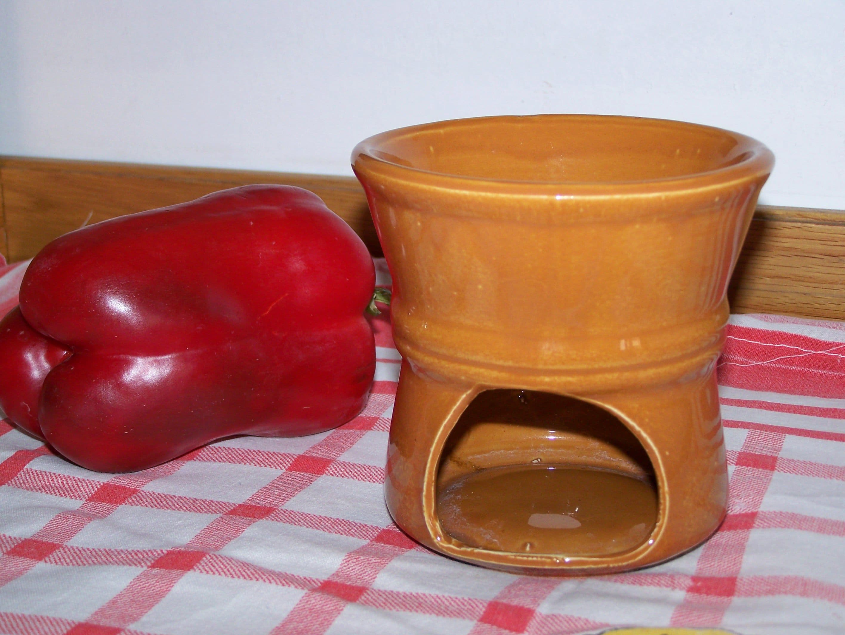 バーニャカウダを食卓で温め続けるための陶器の保温器。下の穴にろうそくを入れ、赤いパプリカが横に添えられている