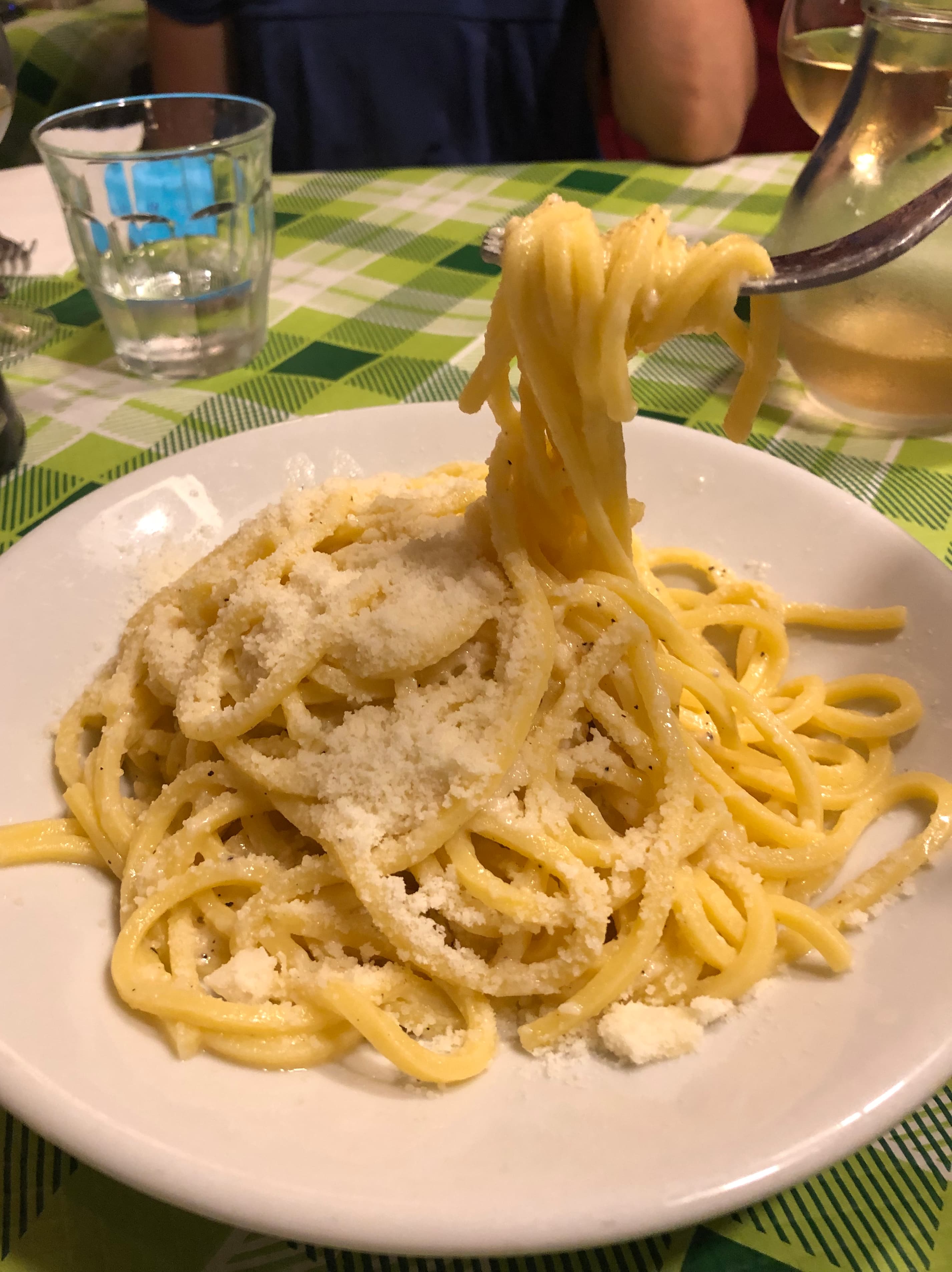 ローマのトラットリアで供されるカチョ・エ・ペペ。フォークでチーズと黒胡椒が絡んだ麺を持ち上げているところ